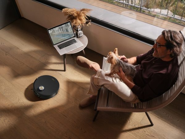 Man relaxing with dog while robot vacuum cleans